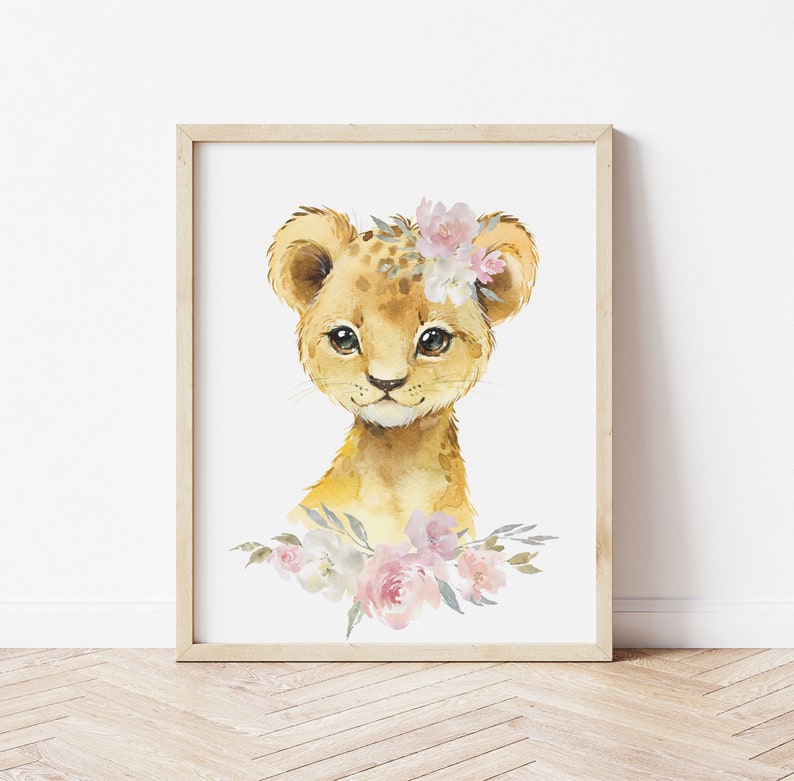 May include: A watercolour painting of a cute lion cub wearing a pink and white flower crown. The lion cub is looking directly at the viewer with big, brown eyes. The background is white.