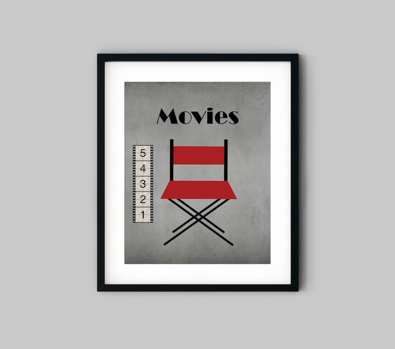 Puede incluir: Una impresi&oacute;n enmarcada en negro con un fondo gris y la palabra "Movies" en texto negro. Una silla de director roja est&aacute; en el centro de la impresi&oacute;n, y una tira de pel&iacute;cula con los n&uacute;meros del 1 al 5 est&aacute; en el lado izquierdo de la impresi&oacute;n.
