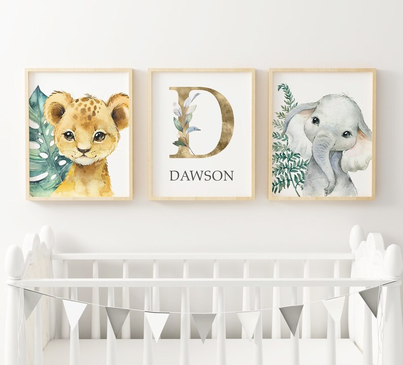 K&ouml;nnte beinhalten: Drei gerahmte Drucke f&uuml;r ein Kinderzimmer. Der erste Druck zeigt eine Aquarell-Illustration eines L&ouml;wenjungen mit gr&uuml;nen Bl&auml;ttern. Der zweite Druck zeigt einen goldenen Buchstaben D mit gr&uuml;nen Bl&auml;ttern und den Namen Dawson. Der dritte Druck zeigt eine Aquarell-Illustration eines Elefanten mit gr&uuml;nen Bl&auml;ttern.