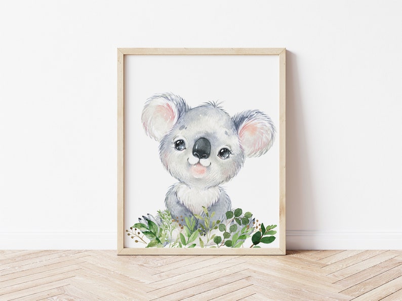 Puede incluir: Una pintura de acuarela de un lindo koala con pelaje gris claro, sentado en un lecho de hojas verdes. El koala tiene una nariz rosada y grandes ojos negros.