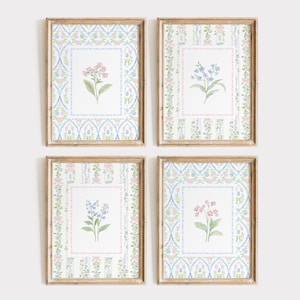 Op de afbeelding: Vier ingelijste bloemenkunstprints. Elke print toont een aquarel bloemillustratie in een rechthoekige lijst. De lijsten zijn omgeven door een patroon in blauw, roze en groen op een witte achtergrond. De lijsten zijn van hout.