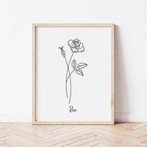 May include: A black and white line drawing of a rose with the word "Rose" written below it. The drawing is framed in a light wood frame.