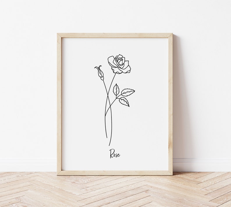 May include: A black and white line drawing of a rose with the word "Rose" written below it. The drawing is framed in a light wood frame.