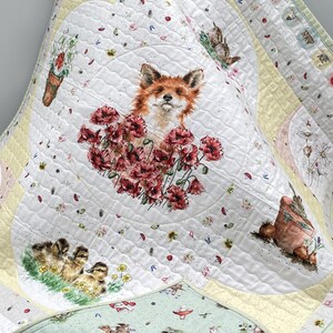 May include: A quilted blanket featuring a whimsical design. The central image showcases a fox surrounded by red flowers. Additional illustrations include ducklings, a rabbit, and floral and woodland elements. The quilt has a white background with yellow and green borders.