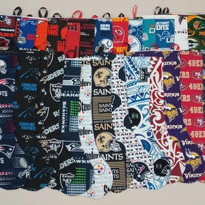 May include: A collection of 15 colorful Christmas stockings featuring various NFL team logos, including the Patriots, Saints, Seahawks, Raiders, 49ers, Packers, and Vikings. The stockings are made of fabric and have a white lining.