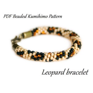 Könnte beinhalten: Ein Perlenarmband mit Leopardenmuster. Das Armband besteht aus schwarzen, beigen und braunen Perlen. Das Armband ist auf weißem Hintergrund abgebildet. PDF Beaded Kumihimo Pattern Leopard bracelet