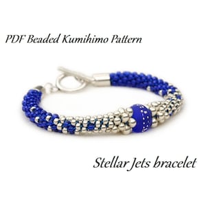 May include: A beaded Kumihimo bracelet with a toggle clasp. The bracelet features blue and silver beads, with a central blue bead with white speckles. The text "Stellar Jets bracelet" is below the bracelet.