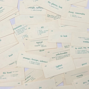 Può includere: Primo piano di una pila di schede bianche con testo verde. Le schede contengono varie parole e definizioni, come "tipico", "questi", "incredibile", "schiarente", "costare", "ospite", "vicinanza", "questo", "gioia", "scritto", "strano", "straniero", "sconosciuto", "frutta", "la testa", "riempire", "lo sguardo", "guardare", "economico", "ragionevole", "guardare", "conosciuto", "abbastanza", "sufficiente", "capelli".