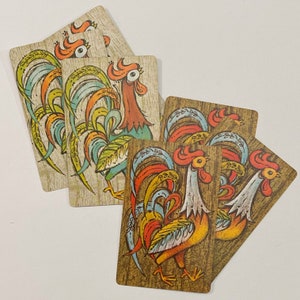 May include: A set of six vintage playing cards featuring colorful illustrations of roosters with intricate patterns. The cards are printed on a textured paper stock and have a retro aesthetic.