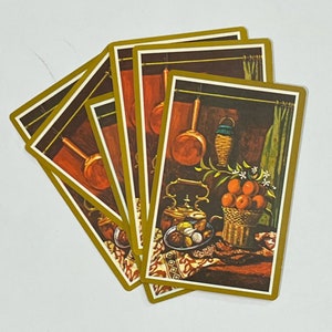 May include: Five vintage playing cards with a gold border and a brown background. The cards feature a still life image of a copper kettle, a basket of oranges, a wicker basket, and a copper pot hanging from a hook.