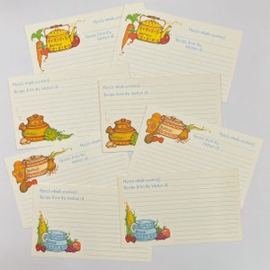 Puede incluir: Conjunto de ocho tarjetas de recetas con un patrón de cuadros azules y blancos. Cada tarjeta presenta una ilustración diferente de una escena de cocina con una tetera, una fuente para hornear y una variedad de verduras y frutas. El texto "¡Aquí se cocina! Receta de la cocina de..." está impreso en cada tarjeta.