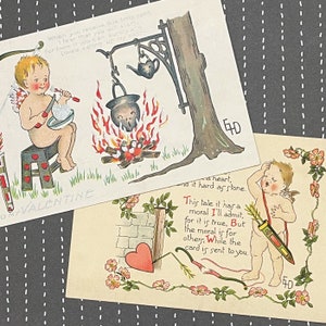 May include: Two vintage Valentine's Day postcards featuring cherubs. The first postcard shows a cherub cooking over a fire with the text "My Valentine". The second postcard shows a cherub with an arrow and the text "This tale it has a moral I'll admit, for it is true, But the moral is for others, While the card is sent to you."