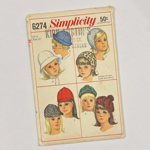 Könnte beinhalten: Ein Vintage-Schnittmuster von Simplicity für Kinderhüte. Das Schnittmuster ist für die Größe 21 Zoll und umfasst sechs verschiedene Hutmodelle: einen Glockenhut, eine Baskenmütze, eine Pixie, eine Haube, einen Eimerhut und eine Mütze. Das Schnittmuster stammt aus den 1960er Jahren und zeigt eine Vintage-Illustration von Kindern, die die Hüte tragen.