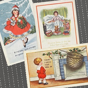 Może przedstawiać: Trzy vintage kartki świąteczne z ilustracjami dzieci. Pierwsza kartka przedstawia dziewczynkę w czerwonej sukience trzymającą wieniec i prezenty w śnieżnym krajobrazie. Druga kartka przedstawia chłopca w piżamie w łóżku z pluszowym misiem i bębnem. Trzecia kartka przedstawia chłopca w czerwonym garniturze stojącego przed kominkiem z wiszącą pończochą. Tekst na kartkach brzmi "A Merry Christmas A Happy", "Christmas fairies, so they say Follow Santa in his sleigh", i "THERE! I GUESS THAT WILL DO".