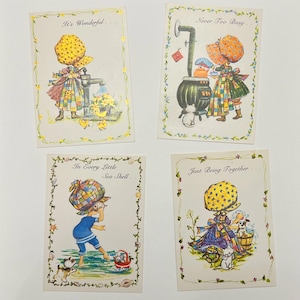 May include: Set of four vintage greeting cards featuring illustrations of a girl in different settings. The cards have a white background with a green floral border and feature the following text: "It's Wonderful...", "Never Too Busy...", "In Every Little Sea Shell...", and "Just Being Together...".