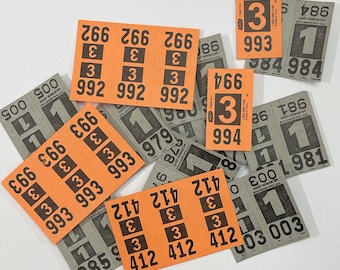 May include: An assortment of orange and gray tickets with black numbers and text. The orange tickets have the numbers 266, 412, 992, and 993. The gray tickets have the numbers 1, 500, 979, and 981.
