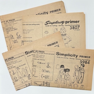 Puede incluir: Un conjunto de guías de patrones de costura vintage Simplicity para la confección. Los patrones están impresos en papel marrón y presentan ilustraciones de diseños de ropa. Los números de patrón son 3807 y 5984.