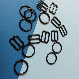 Peut inclure: Un ensemble de boucles coulissantes et d'anneaux en métal noir sur un fond bleu et bleu clair.