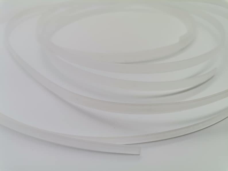 May include: A close-up of a white, flexible, and translucent tube. The tube is coiled and appears to be made of a soft material.