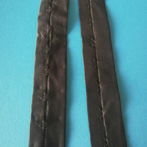 May include: Two black elastic straps with a row of stitching down the center.