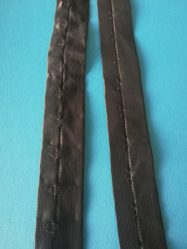 May include: Two black elastic straps with a row of stitching down the center.