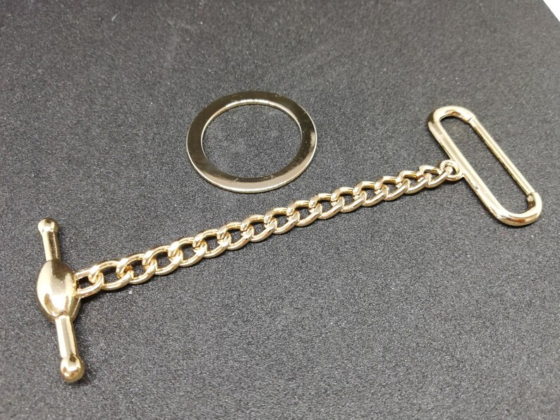 Puede incluir: Una cadena dorada con un anillo redondo, un cierre de palanca y un anillo en D. La cadena mide aproximadamente 30 cm de largo.