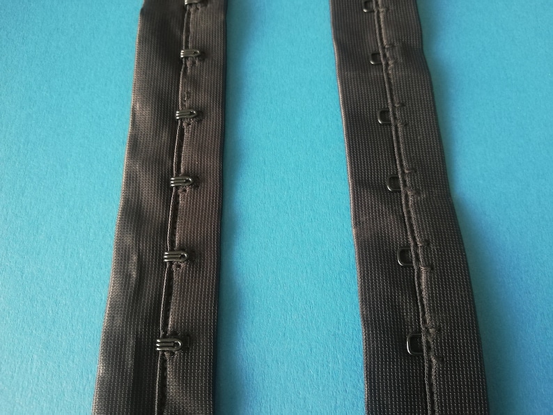 May include: Two black elastic bra straps with metal hooks and eyes for adjusting the fit.