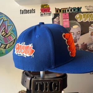 MF DOOM specialdesignad kungblå snapback-keps med orange fat lace. Underground hiphop.