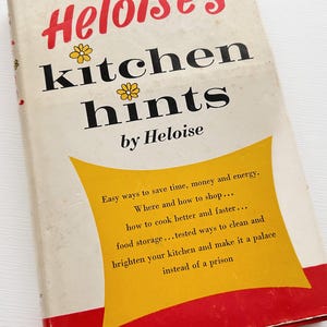 May include: A hardcover book titled Heloise's kitchen hints by Heloise with a white cover featuring red text, black lettering, and yellow flower illustrations. A central yellow graphic contains text about saving time, money, and energy.