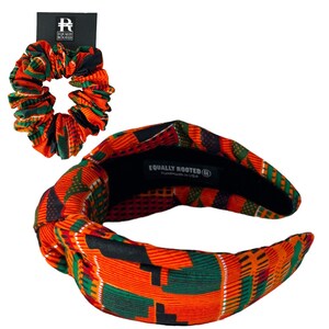 May include: A matching set of hair accessories, including a headband and a scrunchie. Both items display an orange, green, and black geometric pattern. The headband is knotted. The scrunchie is gathered. The headband has the text "Equally Rooted" and "Handmade in USA".