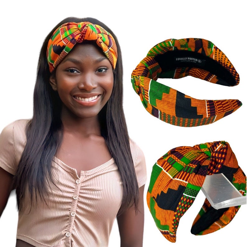 May include: A woman wearing a patterned knotted headband in shades of orange, green, and black. The headband is made of fabric and has a wide band. The text "EQUALLY ROOTED" is visible on the inside of the headband.
