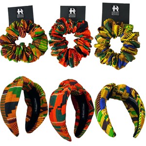 May include: Six hair accessories: three scrunchies and three headbands. The scrunchies and headbands feature vibrant African print fabrics in orange, green, yellow, and blue. Each accessory has a black tag with the text "EQUALLY ROOTED".