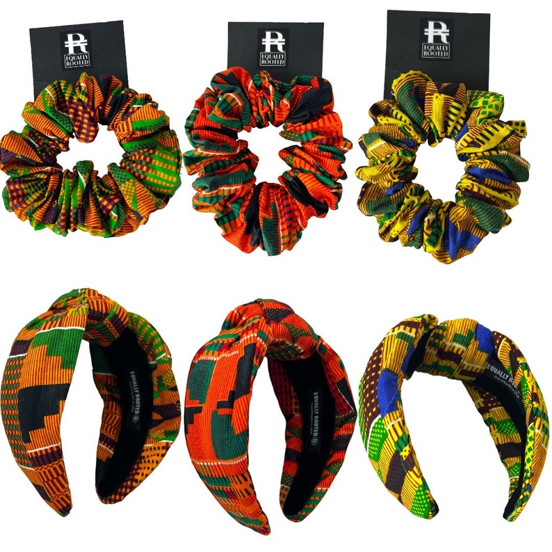 May include: Six hair accessories: three scrunchies and three headbands. The scrunchies and headbands feature vibrant African print fabrics in orange, green, yellow, and blue. Each accessory has a black tag with the text "EQUALLY ROOTED".