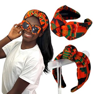 May include: A woman wearing a white t-shirt, sunglasses, and a headband. The headband and sunglasses feature a bright orange, green, and black patterned fabric. Two additional headbands are displayed, showcasing the same colourful design.