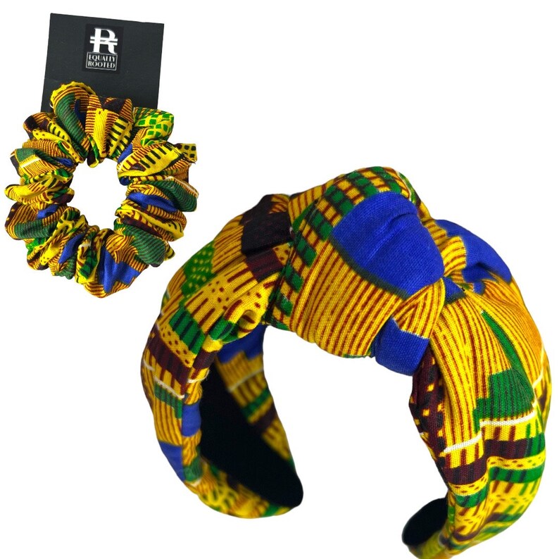 May include: A scrunchie and headband set with a yellow, blue, and green geometric pattern. The headband has a knotted design. The scrunchie and headband are made of fabric. A black tag with white text is visible.