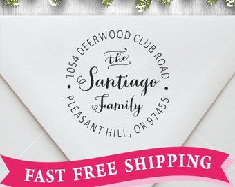 May include: A round return address stamp with the text "1054 Deerwood Club Road, The Santiago Family, Pleasant Hill, OR 97455". The stamp is on a white envelope with a red ribbon that says "Fast Free Shipping".