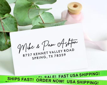 May include: White card with black text. The text reads "Mike & Pam Ashton 8727 Kennet Valley Road Spring, TX 78359". The card is on a white surface with green leaves in the background.