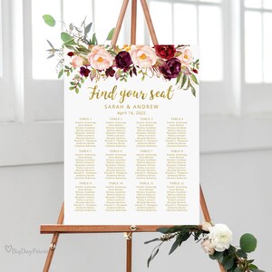 May include: A wedding seating chart with a floral design featuring burgundy and pink flowers. The chart is titled "Find your seat" and lists the names of guests assigned to each table. The text is in gold lettering.