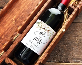 Può includere: Una scatola di legno per vino con una bottiglia di vino rosso all'interno. La bottiglia ha un'etichetta bianca con un motivo floreale e il testo "Mr. and Mrs. Emily and Andrew 04.12.2022 Cheers to the Love & Happiness".