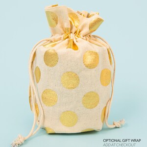 Puede incluir: Una bolsa de cord&oacute;n blanco con lunares dorados. La bolsa est&aacute; hecha de una tela suave y natural y tiene un dise&ntilde;o simple y elegante.