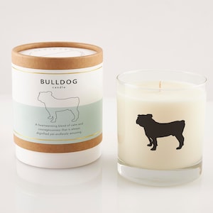 Puede incluir: Un tarro de vela blanco con una silueta de bulldog negra y el texto "BULLDOG candle" en la etiqueta. La etiqueta tambi&eacute;n incluye el texto "Una mezcla reconfortante de calma y valent&iacute;a que siempre es digna y infinitamente divertida."