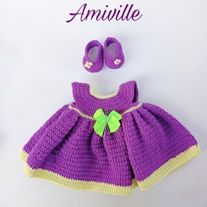 Puede incluir: Amiwille. Conjunto de vestido y zapatos de beb&eacute; de ganchillo, morado con ribete amarillo y lazo verde brillante. El conjunto incluye un vestido y zapatos a juego. El texto "Amiwille" est&aacute; en la esquina superior izquierda.
