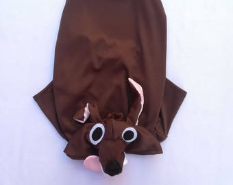 May include: Brown dog costume with a pink nose and large white eyes. The costume has a tail and a hood.