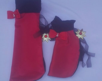 Puede incluir: Dos almohadas con forma de gato rojo y negro con lazos negros y adornos de estrella dorada. La almohada más grande tiene un lazo rojo y la almohada más pequeña tiene un lazo rojo con un strass en el centro.