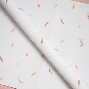K&ouml;nnte beinhalten: Wei&szlig;es Geschenkpapier mit einem sich wiederholenden Muster von Schwimmern in verschiedenen Posen. Die Schwimmer tragen alle Badeanz&uuml;ge und sind in verschiedenen Braunt&ouml;nen, Rosa und Blau dargestellt.