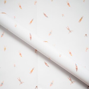 K&ouml;nnte beinhalten: Wei&szlig;es Geschenkpapier mit einem sich wiederholenden Muster von Schwimmern in verschiedenen Posen. Die Schwimmer tragen alle Badeanz&uuml;ge und sind in einem hellrosa, orangefarbenen und blauen Farbschema dargestellt.