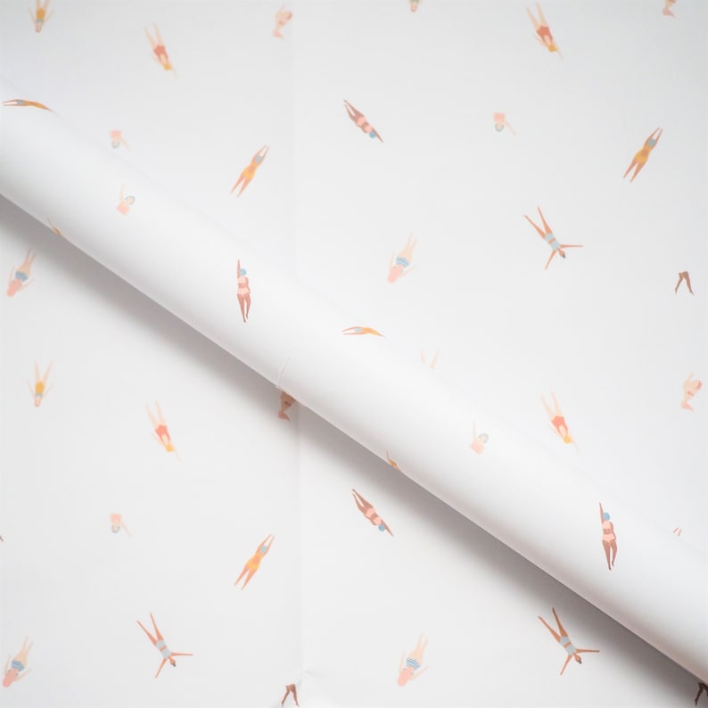 K&ouml;nnte beinhalten: Wei&szlig;es Geschenkpapier mit einem sich wiederholenden Muster von Schwimmern in verschiedenen Posen. Die Schwimmer tragen alle Badeanz&uuml;ge und sind in einem hellrosa, orangefarbenen und blauen Farbschema dargestellt.