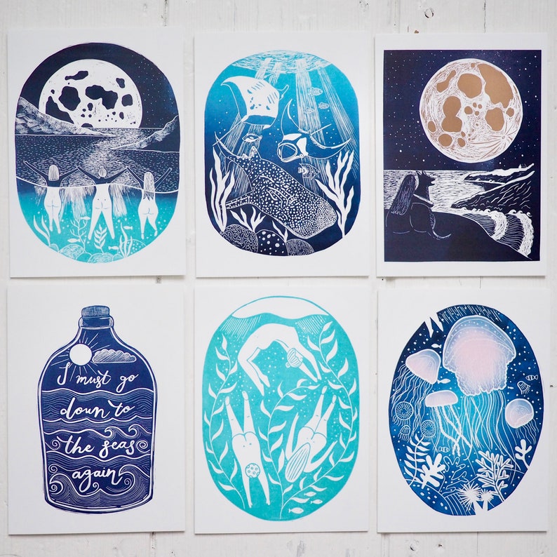 May include: A collection of six art prints featuring ocean-themed illustrations in shades of blue and white. The prints depict scenes such as divers, jellyfish, and a whale shark. One print includes the text "I must go down to the seas again."