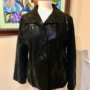 May include: A black, snakeskin-patterned jacket with a button closure. The jacket has a collar and long sleeves.