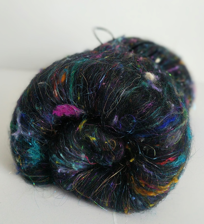 May include: A black yarn with colorful iridescent fibers, perfect for knitting or crocheting.